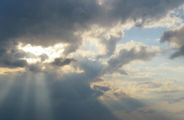 Sun rays shine through dark clouds at sunset, natural background