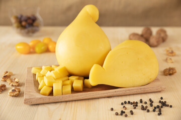 set photo of a typical Italian caciotta, placed on a wooden tray, and cut into cubes. around there are peppercorns, shelled walnuts, olives and yellow cherry tomatoes