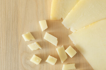 photo of the detail of a typical Italian light-colored cheese, arranged on a wooden cutting board, and cut into cubes. high definition image, for magazines, social networks, websites and advertisement