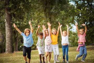 Obraz premium Large group of school kids having fun in nature. Wonderful childhood.