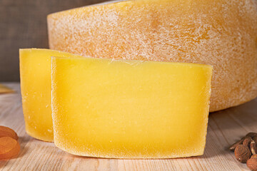 typical Italian yellow paste cheese, on wooden cutting board, almonds, honey, dried peaches. HD image with details for magazines, sites, social networks. kitchens, restaurants and food production