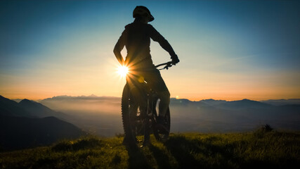 Plakat Silhouette of a woman on mountain bike looking at sunset