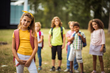 Fototapeta premium Large group of school kids in nature. Portrait of school girl. Focus is on foreground. Group of school children in the park.