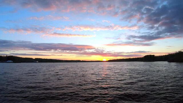 Timelapse colorful sunset. Beautiful panoramic landscape of the river and forest at sunset in orange and blue tones.