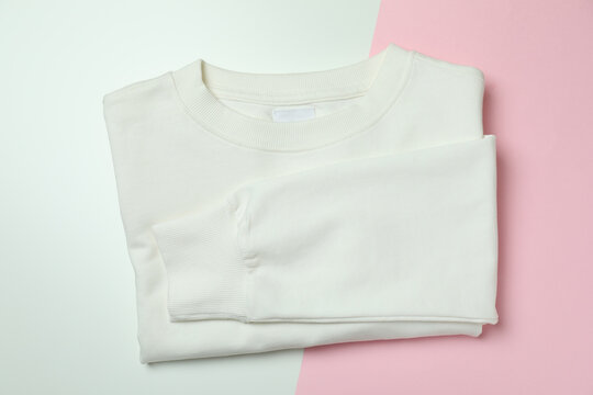 Folded white sweatshirt on two tone background