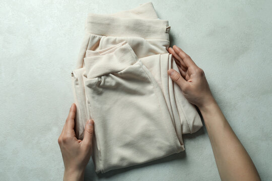 Female hands hold sweatpants on white textured background