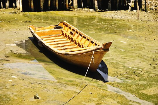 Vintage wooden boat marooned on algae covered mudflats at low tide in Malaysia