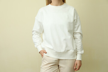 Young woman in white sweatshirt against beige background