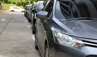 Closeup of front side of dark gray car with  other cars parking in outdoor parking area.