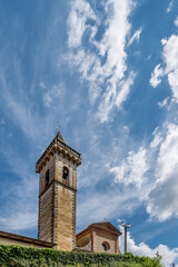 The bell tower and part of the facade of the Santa Croce church in the historic center of Vinci, Florence, Italy, against a dramatic sky