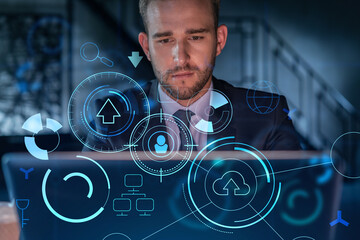 Handsome businessman in suit at workplace working with laptop to optimize development by implying...