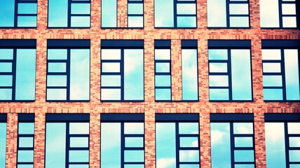 Modern brick and glass facade of the office building.  A contrasting combination of sky and brick texture on a building. Architectural facade of a red brick building. Retro filter.