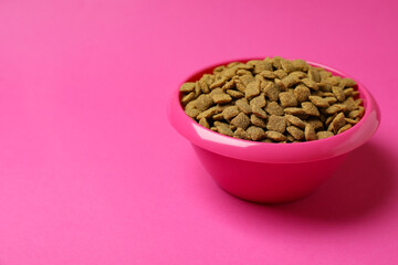 Pet bowl with feed on pink background