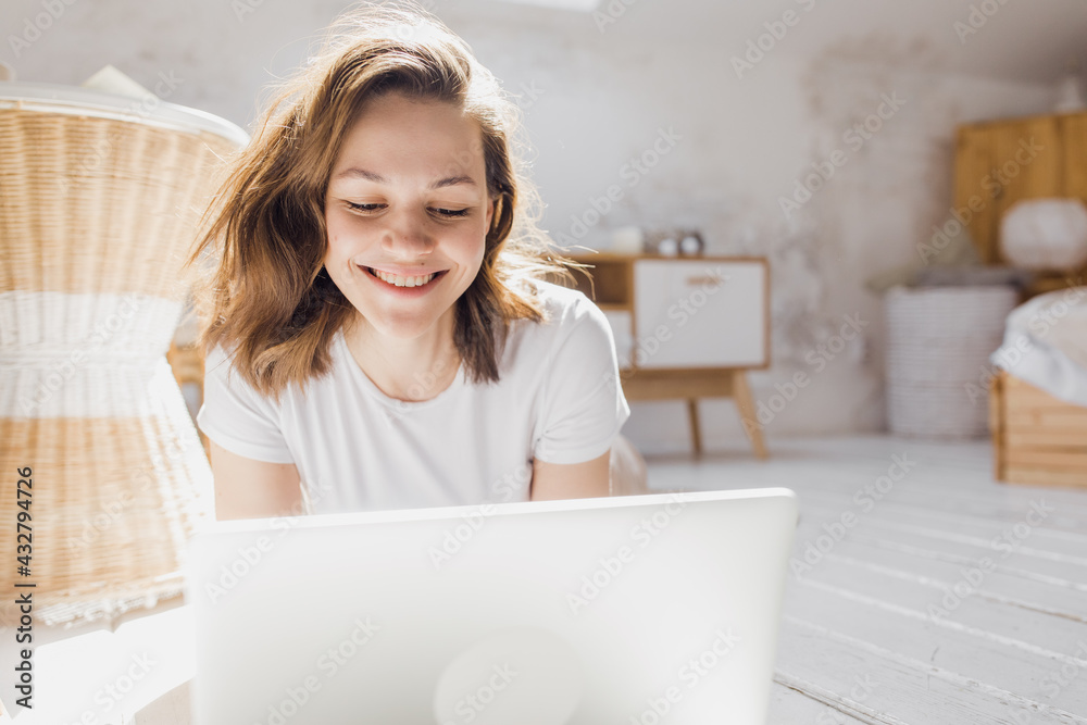 Wall mural attractive african-american girl uses laptop and smiles while sitting on the floor