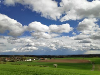 Fototapeta na wymiar A skyscape of clouds over fields and settlement in Bavaria, Germany