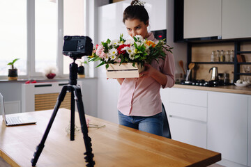 Young female florist record video tutorial of floral compositions design on camera, woman interior...