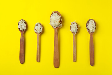Wooden spoons with sauerkraut on yellow background