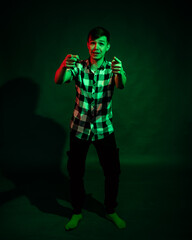 Portrait of a guy in a plaid shirt with red and green light on a black background