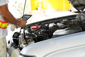 male engineer using a digital tablet to check the engine.