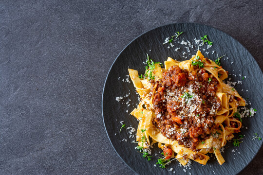 Vegetarian lentil bolognese sauce with Pasta and parmesan cheese on dark table background