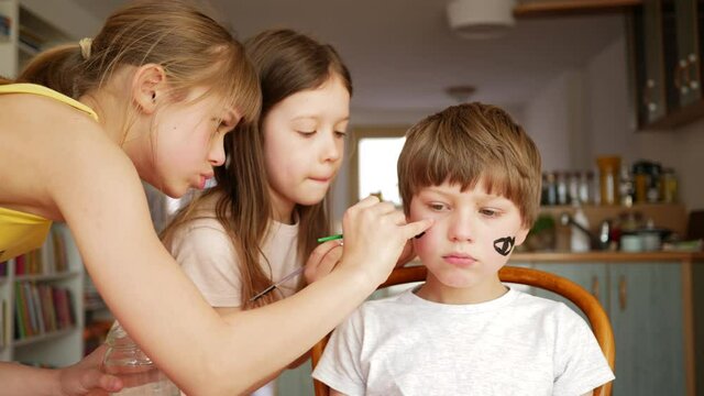 Children stay at home girls painting face to little brother boy