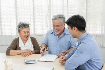 Asian senior man with wife signing contract agreement and discussing with business agent or salesman for family planning future investment for retirement or lifestyle insurance
