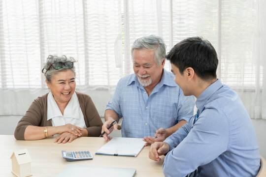 Asian senior man with wife signing contract agreement and discussing with business agent or salesman for family planning future investment for retirement or lifestyle insurance