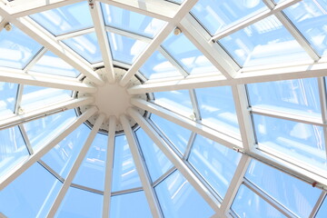 Glass dome with white structure in shopping mall in sunny day.