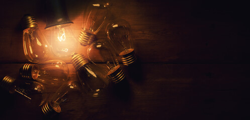 bright idea. glowing filament light bulb on wooden background. copy space