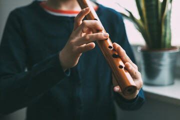 Girl with Peruvian origins performs with a Quena, a traditional wind instrument from South America, especially from Andean areas. - obrazy, fototapety, plakaty