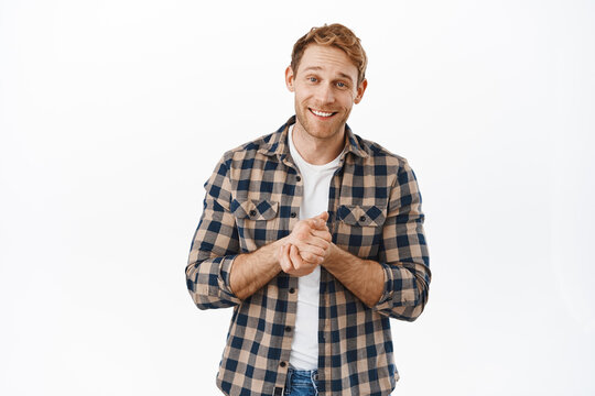 Image of hopeful redhead man smiling, rub hands and asking for favour, begging for help, need something, lending money, standing over white background