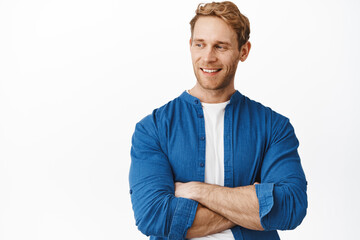 Close up of handsome confident guy with red hair and bristle, cross strong arms over chest, smiling sassy and pleased and looking left, turn head at logo banner copyspace