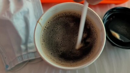 Close-up of  cup of coffee and protective medical mask.  COVID-19, coronavirus pandemic. precautions, prevention, safety measures, health, pandemic covid 19