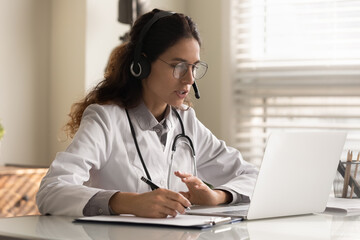 Modern medicine. Focused young female doctor general practitioner in headset watching medical...