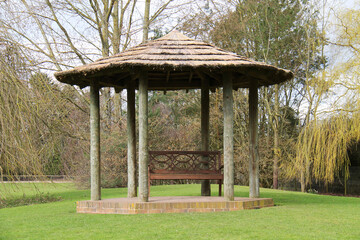 Thatched Shelter with a Wooden Seat in a Garden Setting.