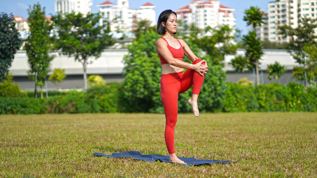 asian chinese female lady yogi practise yoga stretches poses in the park in beautiful weather