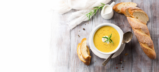 Autumn Vegetable cream soup in white bowl and bread toasts on rustic wooden table.