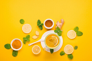 Turmeric milk drink with fresh  mint, ginger, lemon, honey on paper yellow background.