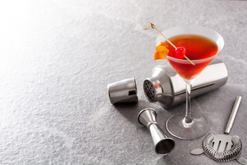 Traditional Manhattan cocktail with cherry on gray stone. Copy space
