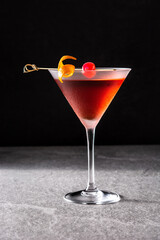 Traditional Manhattan cocktail with cherry on gray stone