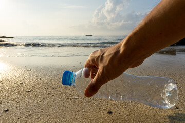 Hand picking up plastic bottle on th beach