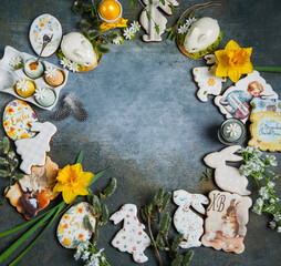 On a blue background, Easter decor, Easter bunnies, eggs, flowers, willow. The objects are placed in a circle. Space for the text.