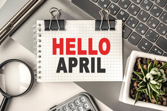 HELLO APRIL text on a notepad and laptop, office tools. Business, financial concept. remote training. Coffee break, ideas, notes, goals or writing a plan, invitation concept. Top view, flat lay.