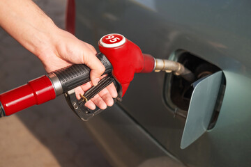Refueling the car with fuel. A red fuel nozzle is installed in the gas tank of a passenger car. On...