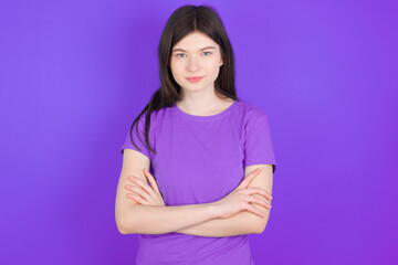 Obraz premium Self confident serious calm young beautiful Caucasian girl wearing purple T-shirt over purple background stands with arms folded. Shows professional vibe stands in assertive pose.