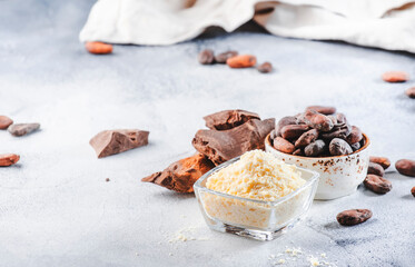 Organic cocoa butter bowl, beans, grated lump on gray table. Copy space