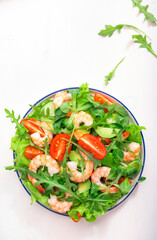 Summer shrimp salad with tomatoes, lettuce, arugula, avocado, cucumber and lemon dressing on white background. Healthy eating, clean food