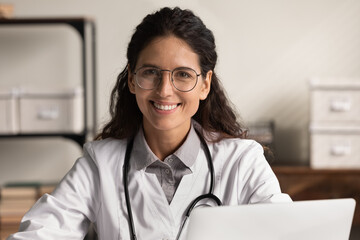Young doctor portrait. Head shot of friendly confident latina female family therapist gp in glasses...