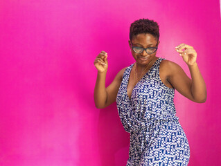 Woman dancing to music in her room against a pink wall.