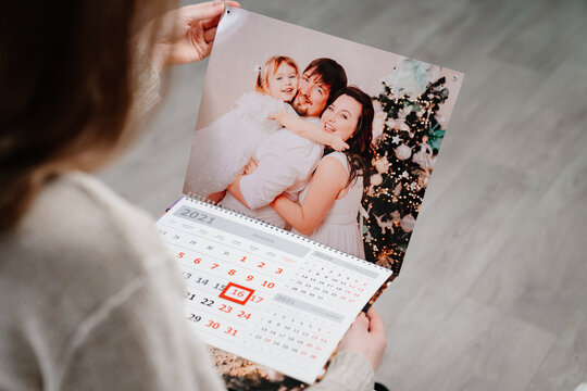 A woman looks at a calendar with a family photo. 